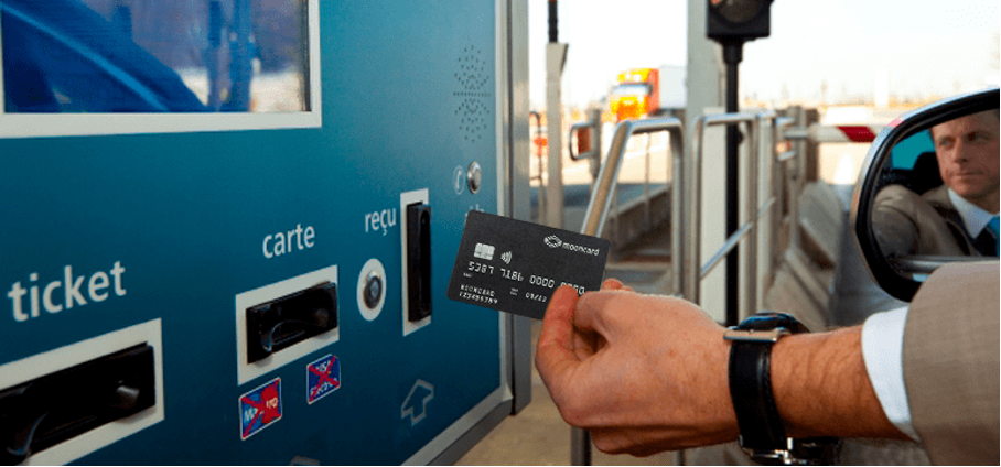 Man in car using an oil card at a toll booth